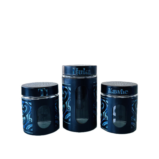 Three black canisters with Māori design Labelled Ti, Kawhe, Huka 