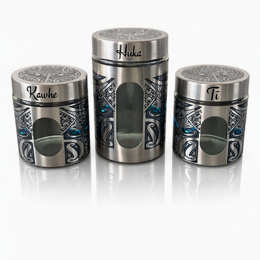 Three stainless steel spice jars with Polynesian tribal patterns and paua accents, labeled Kawhe, Huka, and Ti, on a silver reflective background